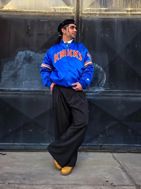 Modelo con campera satinada azul y pantalón rayado ancho