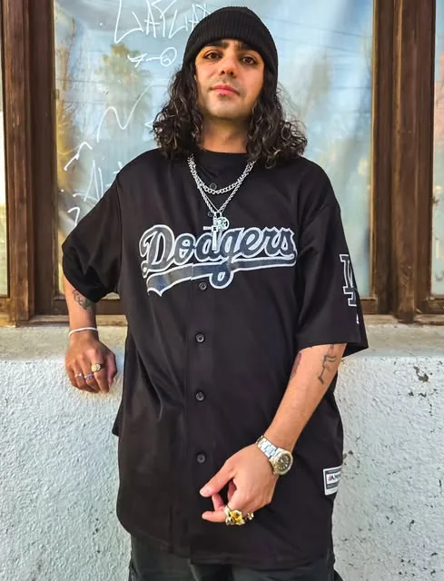 Modelo con camiseta de béisbol negra y cadenas plateadas