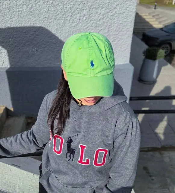 Modelo con buzo canguro gris y gorra verde
